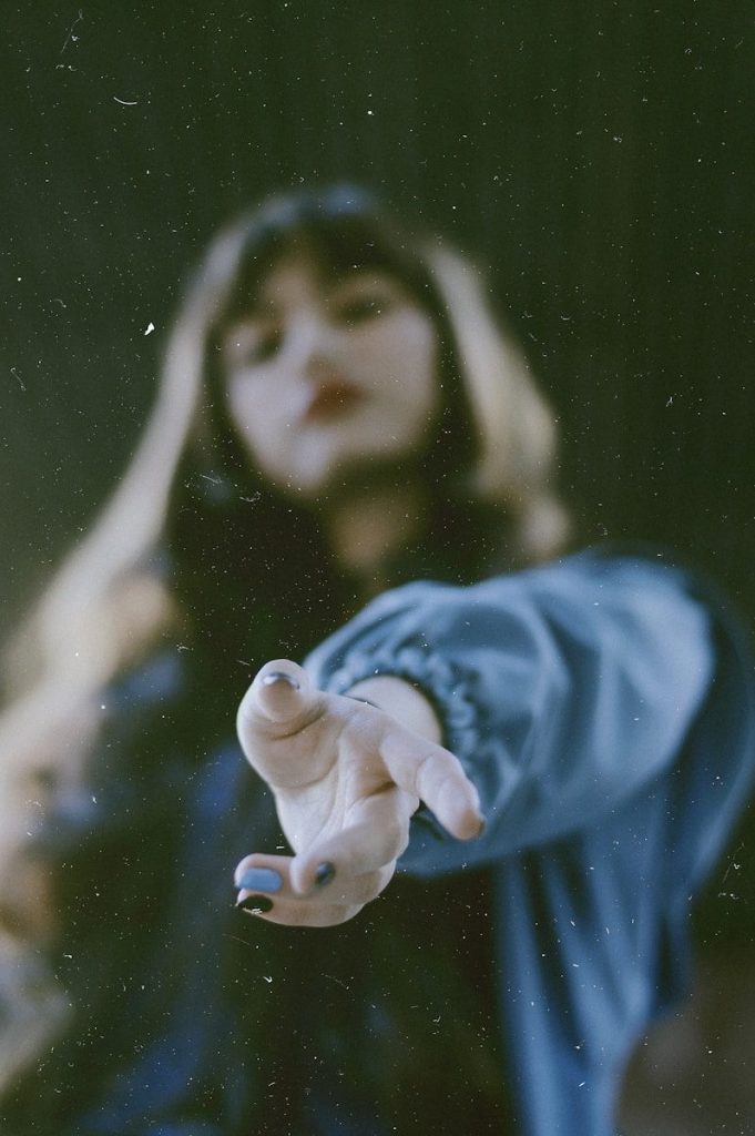 woman in blue jacket reaching out using left hand
