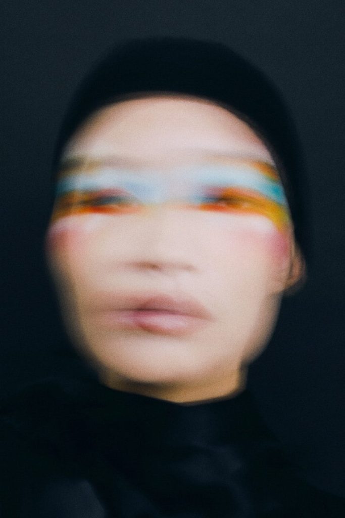 Person with colorful eye makeup against dark background
